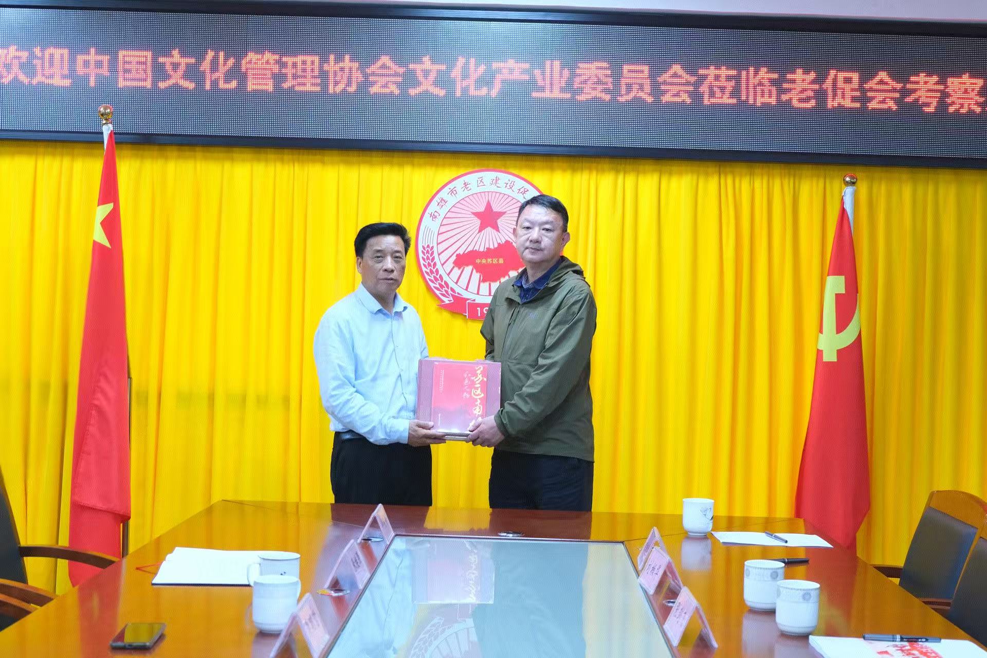 涂运发会长向徐飞副秘书长赠送南雄市老区建设促进会编辑的史料著作